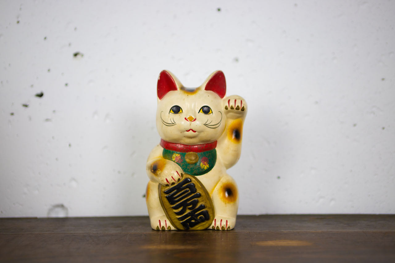 Old beckoning cat piggy bank with open bottom.